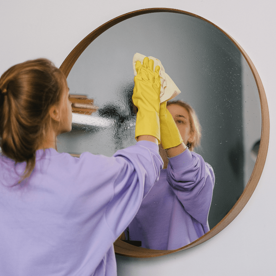 woman wiping a mirror with a microfiber cloth 