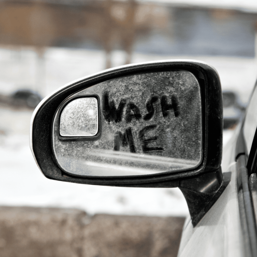 car mirror with wash me written in dirt
