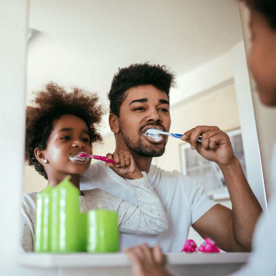 father and daughter brushing their teeth together 
