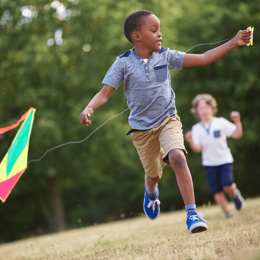 little kid playing flying a kite in the summer 