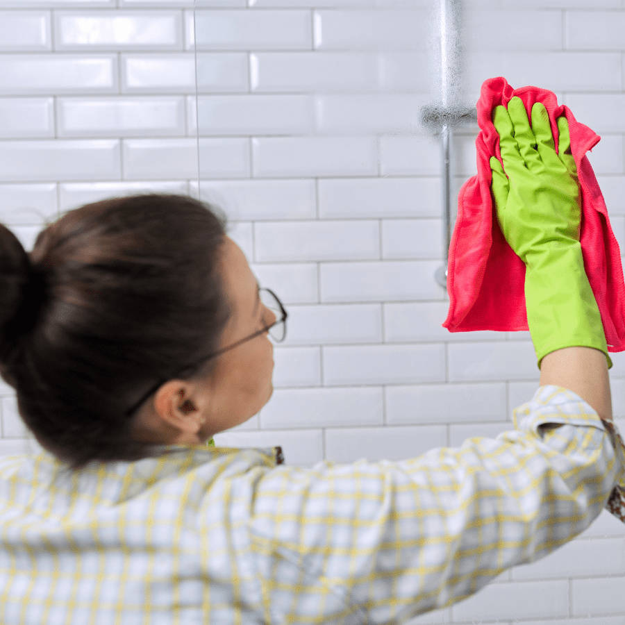 woman cleaning shower soap scum with dishwasher tablet 